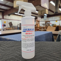 A 16 oz spray bottle of Red 1 Ready-to-Use stain remover by Rosini, shown lying on a gray textured surface in a workshop or warehouse setting.